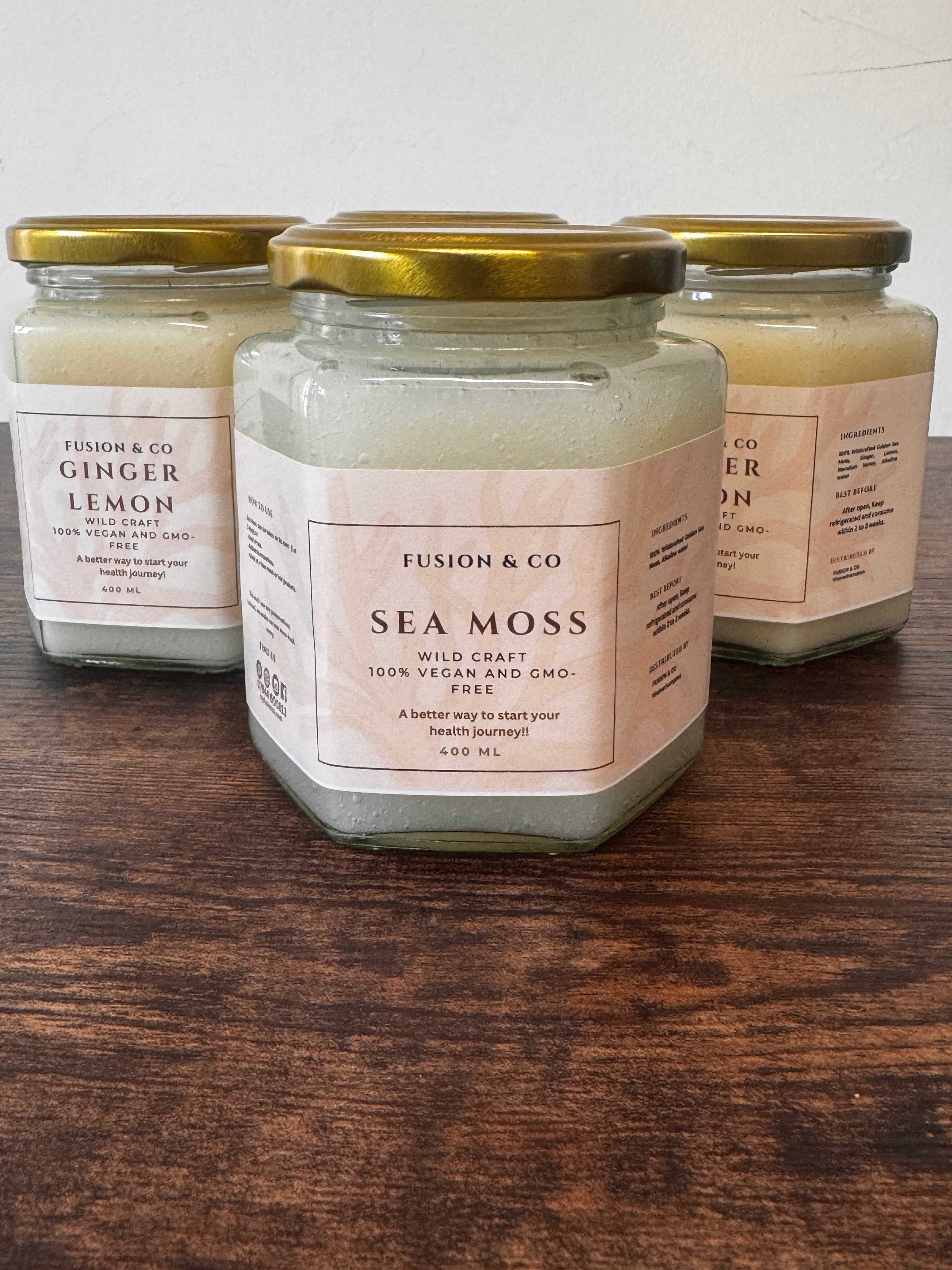 Jars of sea moss gel product with visible labels on a wooden surface